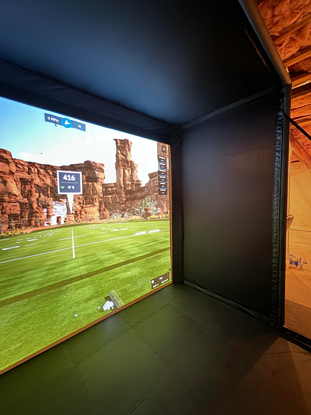 Carl's Place Pro golf simulator enclosure in a basement with GSPro on the screen