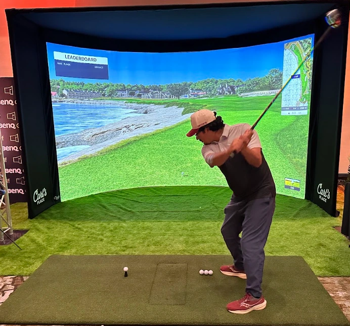 BenQ AK900 golf simulator projector demo bay with a curved screen enclosure at Carl's Place