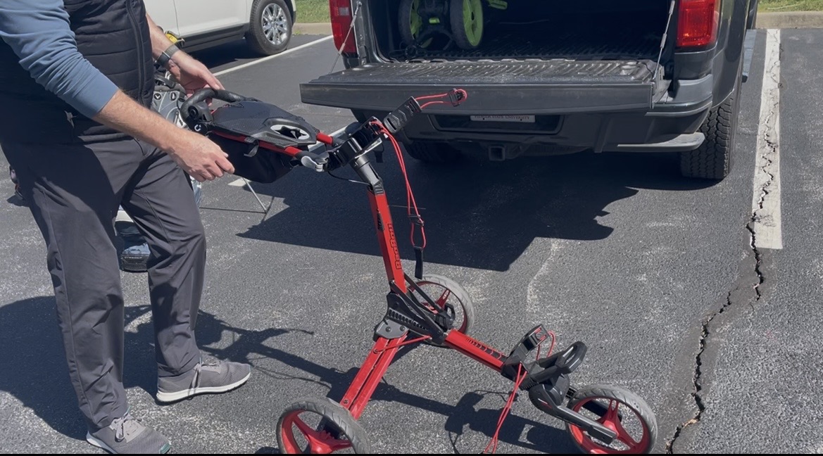 Bag Boy Nitron push cart unfolding in one step in a parking lot